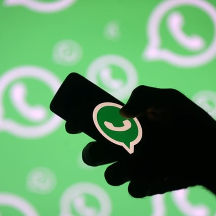 A man poses with a smartphone showing the WhatsApp logo. Photo: Reuters