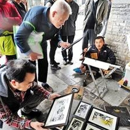 Tang Changyin (seated) pictured selling some of his artwork in Chongqing. Photo: News.china.com