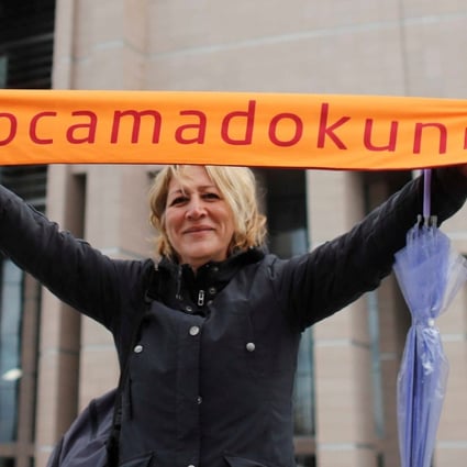 A demonstrator holds a scarf reading “Do not touch my academics” in front of the Justice Palace. Photo: Reuters