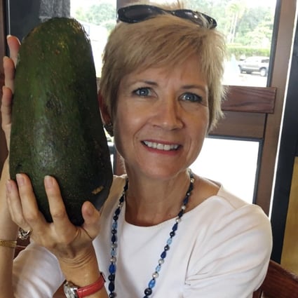Pamela Wang poses for a photo in Kealakekua, Hawaii, with a huge avocado she found while on a walk. Photo: AP