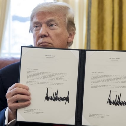 US President Donald Trump holds up a bill after signing it in Washington, on December 22, 2017. Trump signed the tax bill, a continuing resolution to fund the government, and a missile defence bill. Photo: EPA-EFE