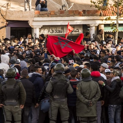 Moroccans shout slogans and wave a national flag as they participate in a demonstration after the funeral of two brothers who died while working in an abandoned coal mine in the northeastern city of Jerada. Photo: Agence France-Presse