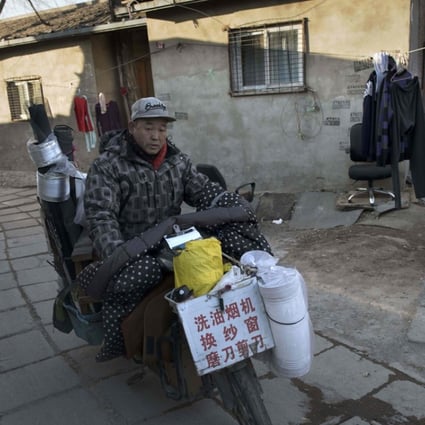 A cooker hood cleaner rides his bike through a migrant village on the outskirts of Beijing. Photo: AFP