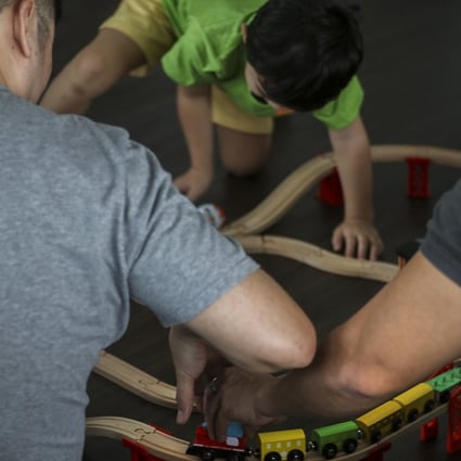 Shawn, left, James, right, and their son Noel, centre, play with a toy train they got Noel for Christmas. The two men are fighting for the right to keep in Singapore their son, the biological son of James and a surrogate mother in the United States. Photo: Don Wong