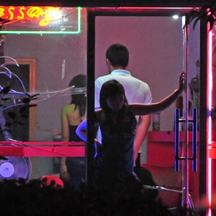 A woman awaits customers from the doorway of a neon-lit barber shop in Beijing in 2008. Sex workers ply their trade in bars, massage spas, karaoke parlours and the barber shops that are found in many Beijing back alleys. Photo: AFP