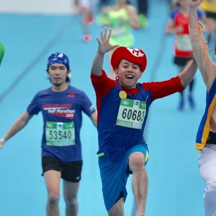 Runners dressed in Super Mario costumes cross the Hong Kong Marathon finish line at Victoria Park. Photo: Nora Tam