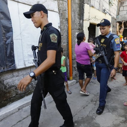 Philippine police walk through a local community as part of the anti-drugs campaign in Quezon City. Photo: EPA
