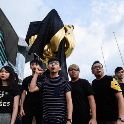 Demosisto party members, including Agnes Chow (left) and Joshua Wong (centre), shout slogans after covering the Golden Bauhinia statue with a black cloth last June, ahead of the 20th anniversary of the city's handover from Britain to China on July 1. Photo: AFP