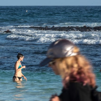 Tourists swim at Tortuga Bay beach in the Galapagos. Ecuador needs tourism dollars, but at what cost? Photo: AFP