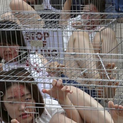 South Korean animal rights activists confine themselves in cages during a campaign opposing South Korea's culture of eating dog meat in Seoul, South Korea. Photo: AP/Ahn Young-joon