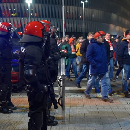 Spartak fans walk past Basque autonomous police officers outside the San Mames stadium after the Europa League clash between Athletic Bilbao and Spartak Moscow. A police officer died at the scene of some crowd trouble. Photo: AFP