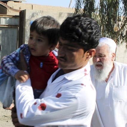 Men carry children away from an explosion site in Lashkar Gah, the capital of the southern Helmand province, in Afghanistan on Saturday. Photo: AP