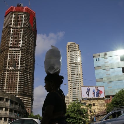 An Indian woman carrying a sack of wheat crosses under construction buildings in Mumbai on Tuesday, June 2, 2015. Photo: AP
