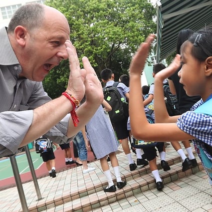 A teacher welcomes his students on the first day of school at Hing Tak School in Tuen Mun. Some recent test results may be an indicator of improving English standards among Hong Kong’s youth. Photo: Edward Wong