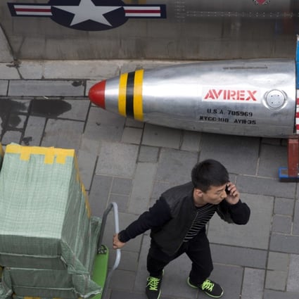 A delivery man calls for directions while pulling a cart of goods past a US apparel store in Beijing on Friday. China is in a spiralling trade dispute with the United States. Photo: AP