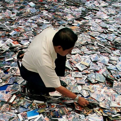 A City Hall worker spreads million of the pirated video compact disc (VCDs), software and CDs on the floor before destroying them in Kuala Lumpur. Photo: AP/Teh Eng Koon