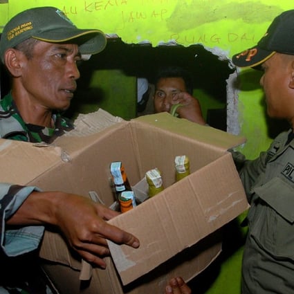 Indonesian police remove bottles of illegal alcohol from a house in Cicalengka district in West Java province on Sunday. More than 60 Indonesians have died from drinking bootleg liquor, police said. Photo: AFP 