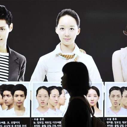 A South Korean woman walks past a street billboard advertising double-jaw surgery at a subway station in Seoul. Photo: AFP