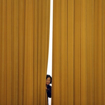 A woman peeps out from behind a curtain ahead of a press conference following a plenary session of China’s National People’s Congress, at the Great Hall of the People in Beijing on March 19. Most people in Western economies know very little of the purposes behind Chinese politics or the meetings of the legislature. Photo: AP