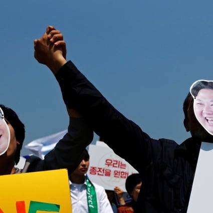 People attending a pro-unification rally in Seoul hold hands as they wear masks of South Korea President Moon Jae-in and North Korean leader Kim Jong-un. Photo: Reuters