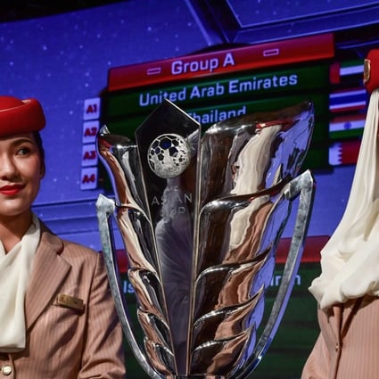 Two Emirates Airlines air hostesses pose next to the AFC Asian Cup trophy during the draw in Dubai. Photos: AFP