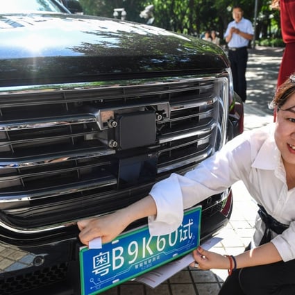 A staff member of Tencent Holdings installs a temporary license plate on a self-driving vehicle for road tests in Shenzhen. Tencent on Monday received a government permit to test its autonomous car on certain public roads in the southern coastal city. Photo: Xinhua