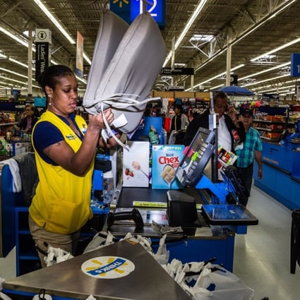 An employee scans a customer's purchases at a Walmart. An alliance of rights groups has released a report claiming that women who work in Asian factories making clothes for the global retail giant are at “daily risk” of slapping, sexual abuse and other harassment. Photo: Bloomberg