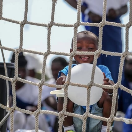 A child plays with a rubber glove on board the Spanish Navy 'Numancia' ship in Palermo, Italy. Photo: EPA