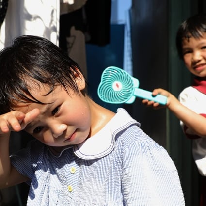 Two children living in a rooftop hut in Tai Kok Tsui try to find relief from the heat during the day on May 29, when temperatures reached 35.3 degrees Celsius. Hong Kong experienced the hottest May on record this year. Photo: Sam Tsang
