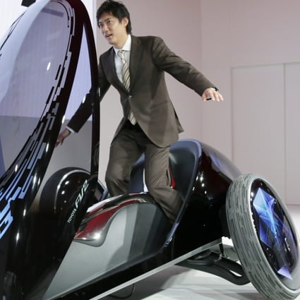 A TV reporter tries to control a Toyota Motor Corp. Toyota FV two in Tokyo, Japan. Photo: EPA