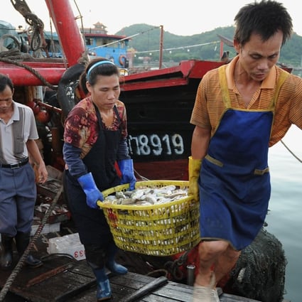 A Chinese fisherman and his wife carry the day’s catch from a boat at a fishing port in Zhuhai in southern China’s Guangdong province. Photo: AFP