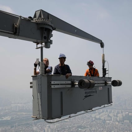 'Urban climber' Alain Robert of France is hoisted to a deck of the Lotte World Tower after scaling the exterior of the building, in Seoul on June 6. Photo: AFP