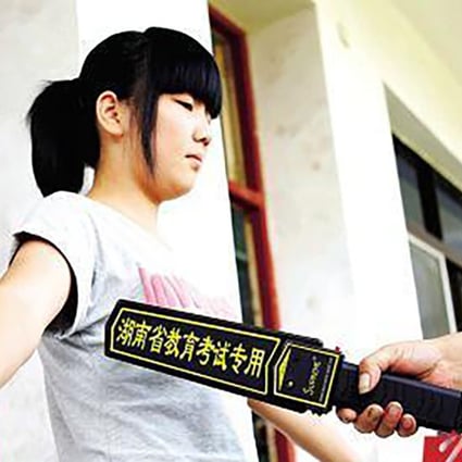 An official uses a metal detection bar to scan students entering the examination room. Photo: Baidu