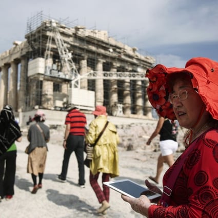 A Chinese tourist carries a tablet device during a visit to the Parthenon at the Acropolis archaeological site in Athens, Greece. Photo: Bloomberg