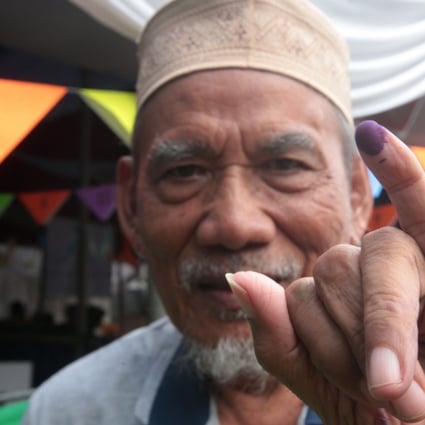 An Indonesian man shows his finger after voting at a polling station in Depok, Indonesia. Photo: EPA