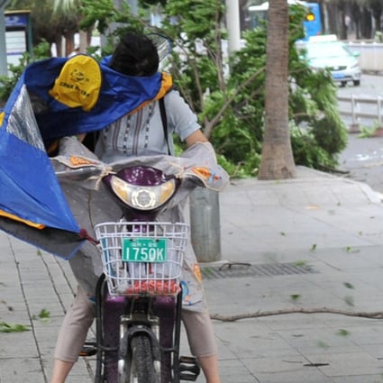 A woman riding an electric bicycle braces herself against strong wind brought by Typhoon Maria on a street in Fuzhou, Fujian province, on Wednesday. Photo: Reuters