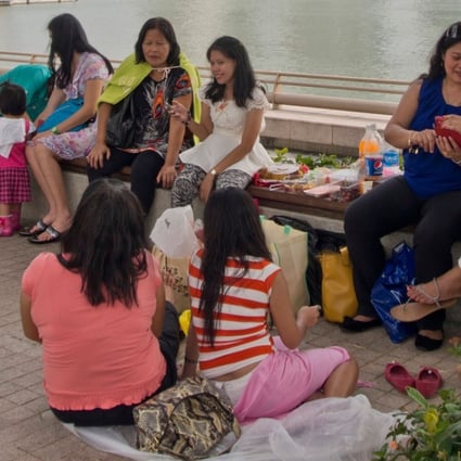 Migrant domestic workers enjoy a day off at Marina Bay in downtown Singapore. Photo: Alamy