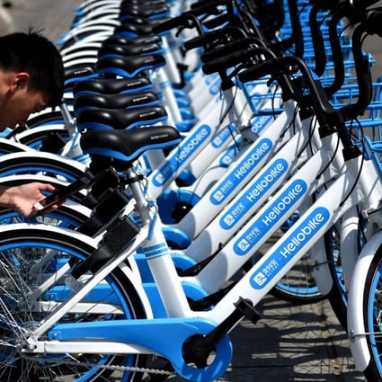 A local resident uses his smartphone to scan a QR code on a bicycle of bike-sharing service provider Hellobike on a street in Luoyang City, in central China’s Henan province. Photo: Imaginechina