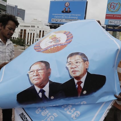 Cambodian workers fold a poster with portraits of Prime Minister Hun Sen and President of the National Assembly Heng Samrin after the national elections in Phnom Penh, Cambodia, July 30, 2018. Photo: EPA