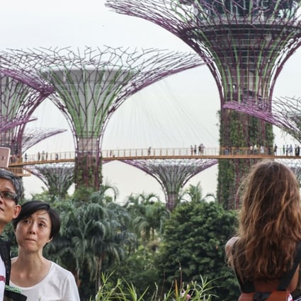 Tourists take pictures and selfies of the Supertree Groves at Gardens by the Bay, a nature park in Singapore. A new app lets you pretend to your social media followers that you were somewhere desirable. Roy Issa