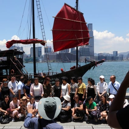 Tourists pose for a photo with a junk boat in the background at the Golden Bauhinia Square in Wan Chai. Photo: Felix Wong