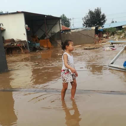 A girl wades through a flooded street in Shouguang on Tuesday after the city was battered by Typhoon Rumbia. Photo: Reuters