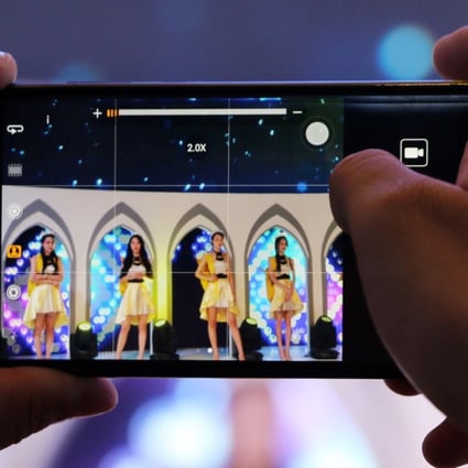 A male attendee takes video of showgirls at the booth of mobile games developer IGN at China's biggest gaming show. Under new rules, all new games will require an operating license. Photo: SCMP/ Zheping Huang