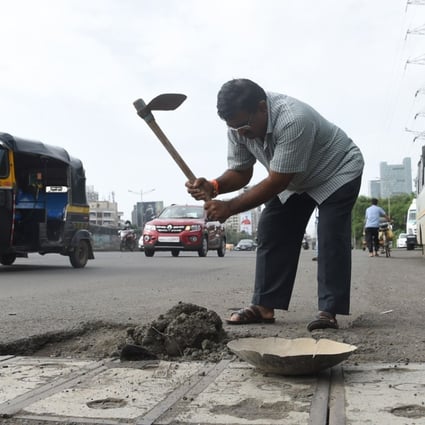 Indian businessman Dadarao Bilhore filling a pothole on the Western Express highway in Mumbai. Photo: AFP