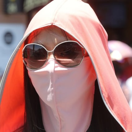 A woman covers up to protect herself from the sun in Tsim Sha Tsui, Hong Kong. Photo: K.Y. Cheng