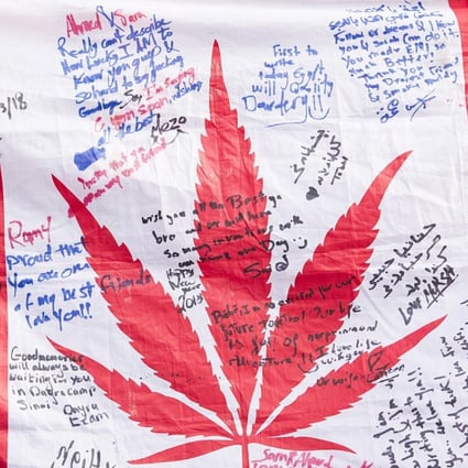 People hold up a Canadian flag with a marijuana logo on it outside a government cannabis store in Montreal. Photo: AP