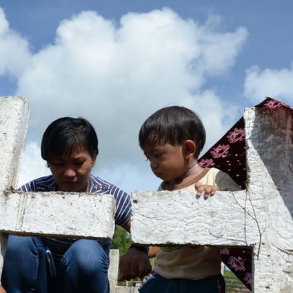 Juvilyn Luana and her son visit the graves of family members who died in Typhoon Haiyan. Photo: AFP