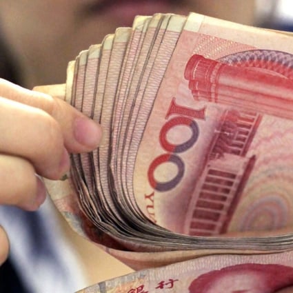 A bank clerk counts a stack of 100 yuan notes in Shanghai. Photo: AP