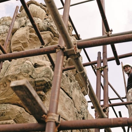 Stonemason Morm Pum, who has been working in temple restoration since 1993, stands on top of a scaffolding at West Mebun temple, Angkor, Cambodia, before work on it was halted. Photo: Enric Catala