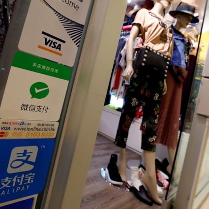 Logos of digital payment services, including WeChat Pay, are displayed outside a boutique at a shopping mall in Hong Kong. Photo: Reuters